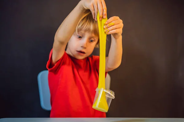 Pojke spelar handgjorda leksak som heter slem. Barn leka med slem. Kid klämma och stretching slem — Stockfoto