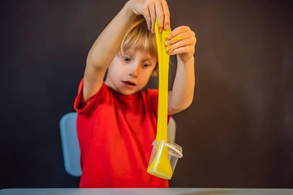 Menino jogando brinquedo feito à mão chamado lodo. Criança brincando com lodo. Kid squeeze e alongamento lodo — Fotografia de Stock