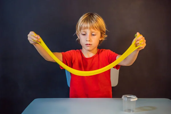 Pojke spelar handgjorda leksak som heter slem. Barn leka med slem. Kid klämma och stretching slem — Stockfoto