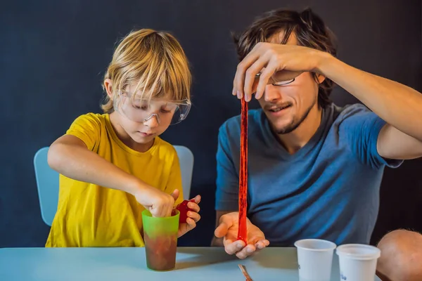 Padre e hijo realizan experimentos químicos en casa. Basura hecha en casa. La familia juega con un limo —  Fotos de Stock