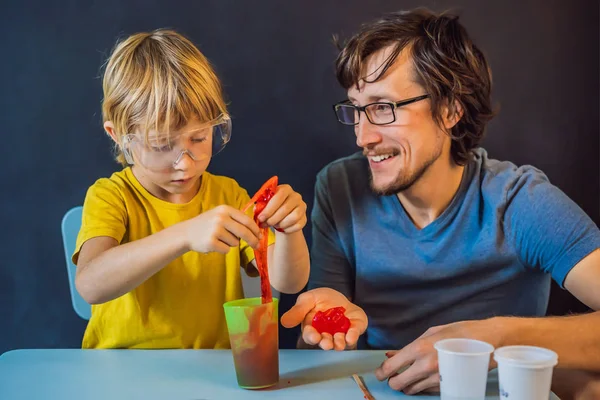 Father and son conduct chemical experiments at home. Home made slime. Family plays with a slime — ストック写真