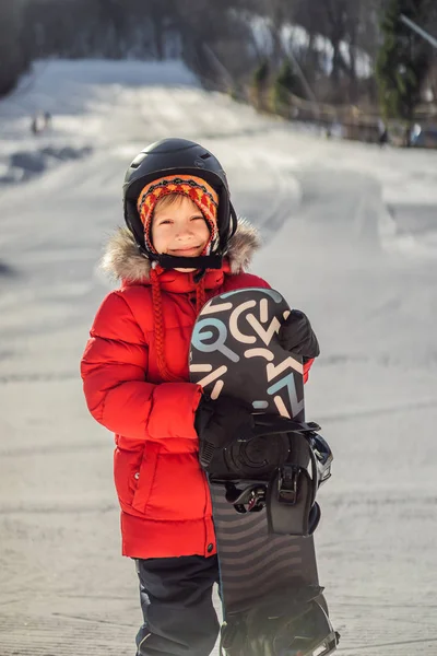 Lilla söta pojken är redo för snowboard. Aktiviteter för barn på vintern. Barnens vintersport. Livsstil — Stockfoto