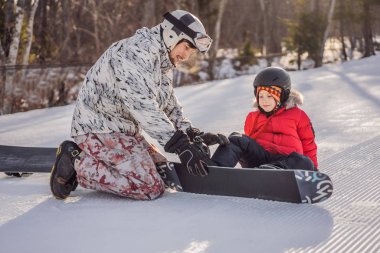 Babası oğluna snowboard öğretiyor. Kışın çocuklar için etkinlikler. Çocuklar kış sporu. Yaşam biçimi