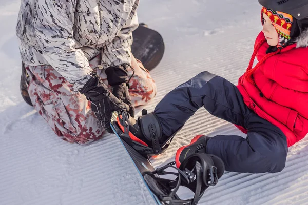 Tata uczy syna snowboardingu. Zajęcia dla dzieci w zimie. Zimowy sport dla dzieci. Styl życia — Zdjęcie stockowe