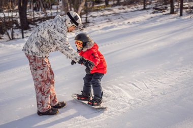 Babası oğluna snowboard öğretiyor. Kışın çocuklar için etkinlikler. Çocuklar kış sporu. Yaşam biçimi