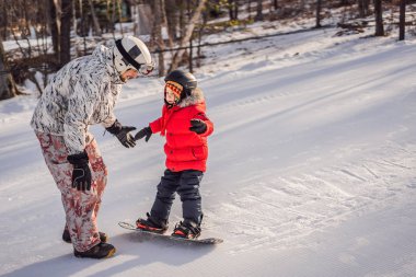 Babası oğluna snowboard öğretiyor. Kışın çocuklar için etkinlikler. Çocuklar kış sporu. Yaşam biçimi