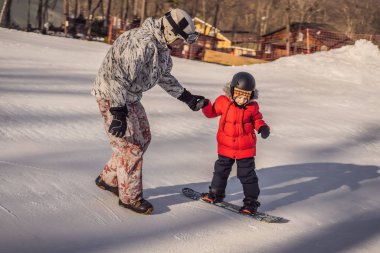 Babası oğluna snowboard öğretiyor. Kışın çocuklar için etkinlikler. Çocuklar kış sporu. Yaşam biçimi