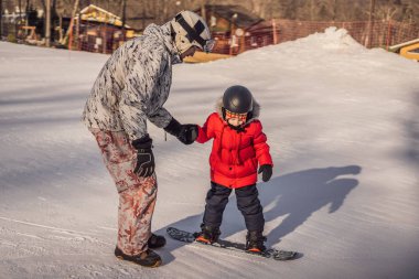 Babası oğluna snowboard öğretiyor. Kışın çocuklar için etkinlikler. Çocuklar kış sporu. Yaşam biçimi