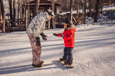 Babası oğluna snowboard öğretiyor. Kışın çocuklar için etkinlikler. Çocuklar kış sporu. Yaşam biçimi