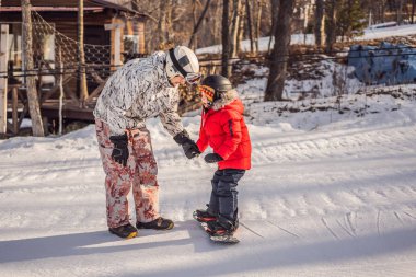 Babası oğluna snowboard öğretiyor. Kışın çocuklar için etkinlikler. Çocuklar kış sporu. Yaşam biçimi