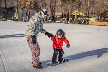 Babası oğluna snowboard öğretiyor. Kışın çocuklar için etkinlikler. Çocuklar kış sporu. Yaşam biçimi