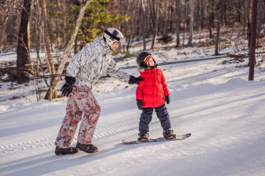 Babası oğluna snowboard öğretiyor. Kışın çocuklar için etkinlikler. Çocuklar kış sporu. Yaşam biçimi
