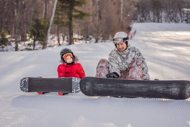 Babası oğluna snowboard öğretiyor. Kışın çocuklar için etkinlikler. Çocuklar kış sporu. Yaşam biçimi