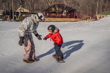 Babası oğluna snowboard öğretiyor. Kışın çocuklar için etkinlikler. Çocuklar kış sporu. Yaşam biçimi