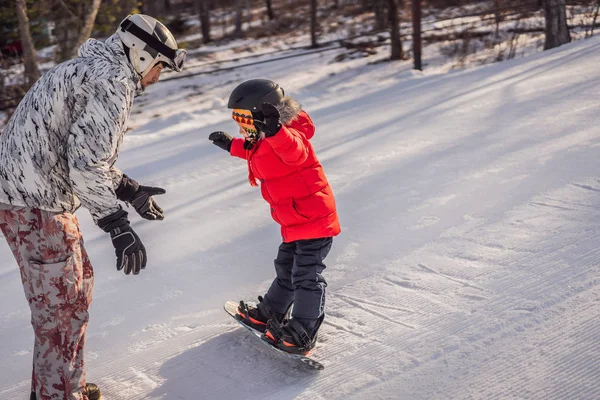 Tata uczy syna snowboardingu. Zajęcia dla dzieci w zimie. Zimowy sport dla dzieci. Styl życia — Zdjęcie stockowe