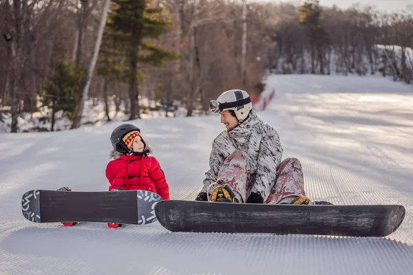 Papá enseña snowboard a su hijo. Actividades para niños en invierno. Deporte de invierno para niños. Estilo de vida — Foto de Stock