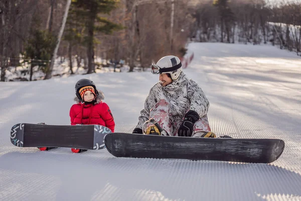 O pai ensina snowboard ao filho. Atividades para crianças no inverno. Desporto de inverno das crianças. Estilo de vida — Fotografia de Stock