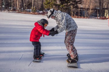 Babası oğluna snowboard öğretiyor. Kışın çocuklar için etkinlikler. Çocuklar kış sporu. Yaşam biçimi