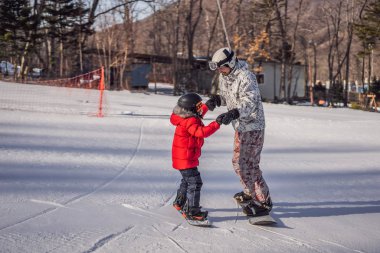 Babası oğluna snowboard öğretiyor. Kışın çocuklar için etkinlikler. Çocuklar kış sporu. Yaşam biçimi