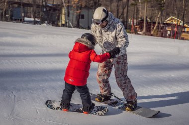 Babası oğluna snowboard öğretiyor. Kışın çocuklar için etkinlikler. Çocuklar kış sporu. Yaşam biçimi