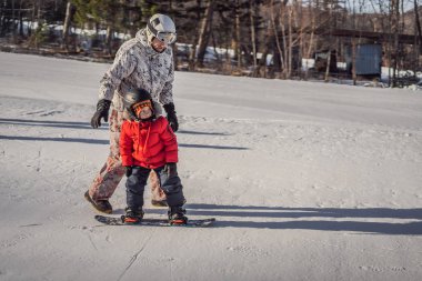Babası oğluna snowboard öğretiyor. Kışın çocuklar için etkinlikler. Çocuklar kış sporu. Yaşam biçimi