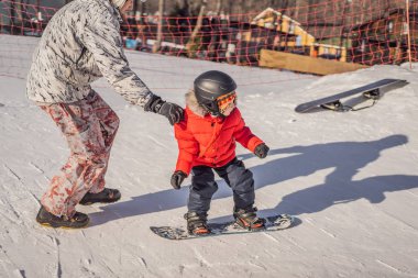 Babası oğluna snowboard öğretiyor. Kışın çocuklar için etkinlikler. Çocuklar kış sporu. Yaşam biçimi