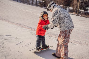 Babası oğluna snowboard öğretiyor. Kışın çocuklar için etkinlikler. Çocuklar kış sporu. Yaşam biçimi