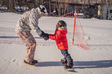 Babası oğluna snowboard öğretiyor. Kışın çocuklar için etkinlikler. Çocuklar kış sporu. Yaşam biçimi