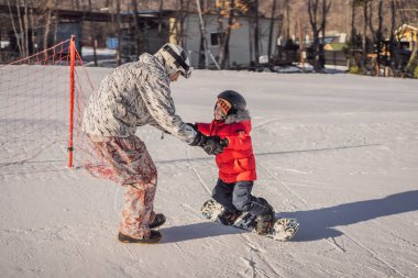 Babası oğluna snowboard öğretiyor. Kışın çocuklar için etkinlikler. Çocuklar kış sporu. Yaşam biçimi