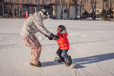 Babası oğluna snowboard öğretiyor. Kışın çocuklar için etkinlikler. Çocuklar kış sporu. Yaşam biçimi