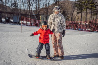 Babası oğluna snowboard öğretiyor. Kışın çocuklar için etkinlikler. Çocuklar kış sporu. Yaşam biçimi