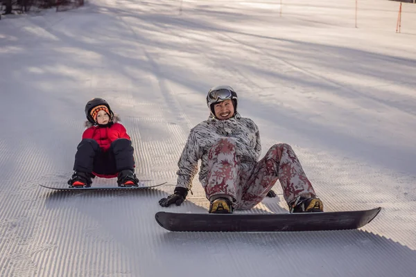 Tata uczy syna snowboardingu. Zajęcia dla dzieci w zimie. Zimowy sport dla dzieci. Styl życia — Zdjęcie stockowe