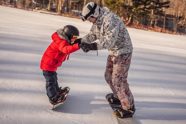 Babası oğluna snowboard öğretiyor. Kışın çocuklar için etkinlikler. Çocuklar kış sporu. Yaşam biçimi