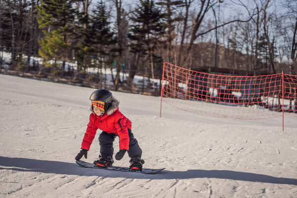 Little cute boy snowboarding. Activities for children in winter. Childrens winter sport. Lifestyle