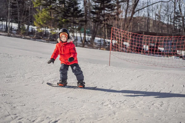 Kleiner netter Junge beim Snowboarden. Aktivitäten für Kinder im Winter. Kinderwintersport. Lebensstil — Stockfoto