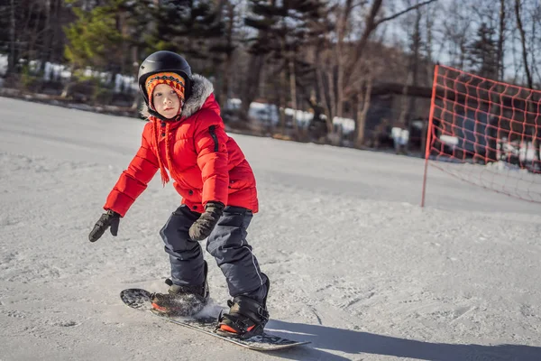 Маленький милый мальчик на сноуборде. Развлечения для детей зимой. Детский зимний спорт. Стиль жизни — стоковое фото