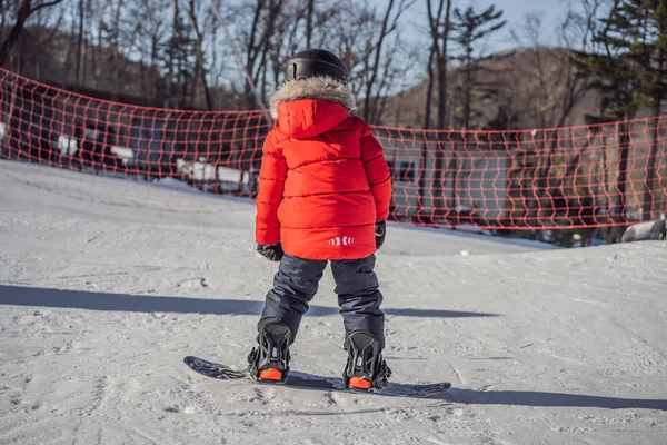 Μικρό χαριτωμένο αγόρι που κάνει σνόουμπορντ. Δραστηριότητες για παιδιά το χειμώνα. Παιδικό χειμερινό άθλημα. Τρόπος ζωής — Φωτογραφία Αρχείου