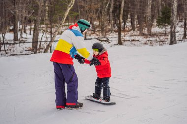 Snowboard eğitmeni bir çocuğa snowboard yapmayı öğretiyor. Kışın çocuklar için etkinlikler. Çocuklar kış sporu. Yaşam biçimi