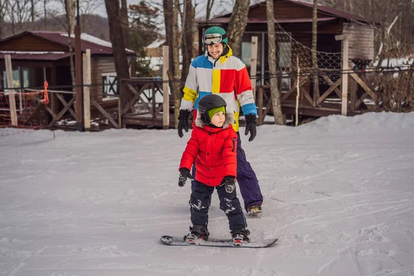 A snowboard oktató megtanít egy fiút snowboardozni. Tevékenységek gyerekeknek télen. Gyermek téli sport. Életmód — Stock Fotó