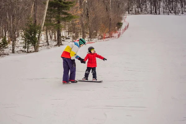 Snowboardlehrer bringt einem Jungen das Snowboarden bei. Aktivitäten für Kinder im Winter. Kinderwintersport. Lebensstil — Stockfoto