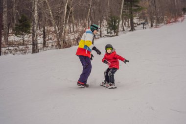 Snowboard eğitmeni bir çocuğa snowboard yapmayı öğretiyor. Kışın çocuklar için etkinlikler. Çocuklar kış sporu. Yaşam biçimi