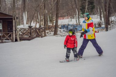 Snowboard eğitmeni bir çocuğa snowboard yapmayı öğretiyor. Kışın çocuklar için etkinlikler. Çocuklar kış sporu. Yaşam biçimi