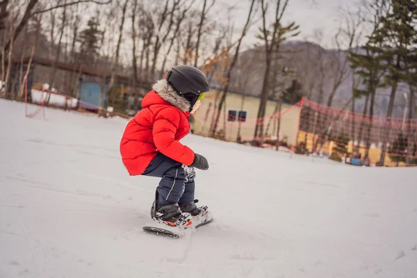 Kleiner netter Junge beim Snowboarden. Aktivitäten für Kinder im Winter. Kinderwintersport. Lebensstil — Stockfoto