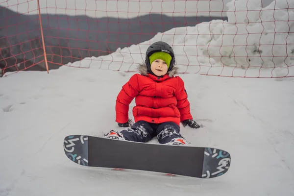Aranyos fiú snowboardozik. Tevékenységek gyerekeknek télen. Gyermek téli sport. Életmód — Stock Fotó