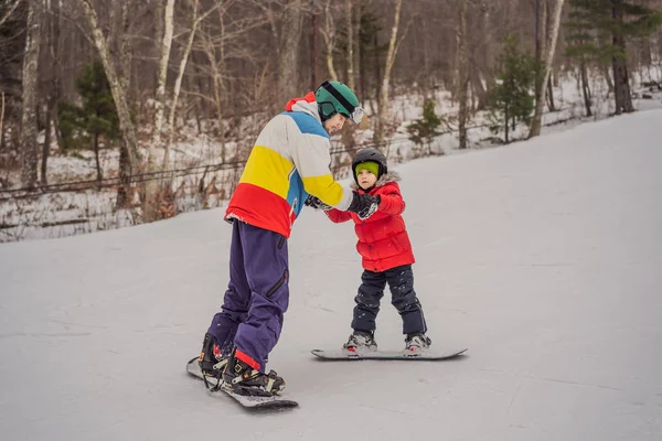 Instrutor de snowboard ensina um menino a snowboard. Atividades para crianças no inverno. Desporto de inverno das crianças. Estilo de vida — Fotografia de Stock