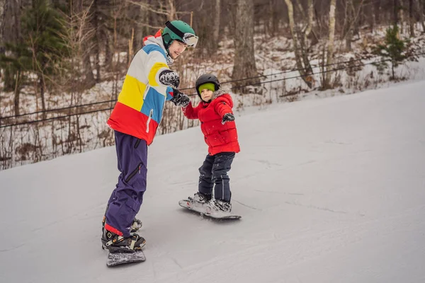 Instruktor snowboardu uczy chłopca jeździć na snowboardzie. Zajęcia dla dzieci w zimie. Zimowy sport dla dzieci. Styl życia — Zdjęcie stockowe