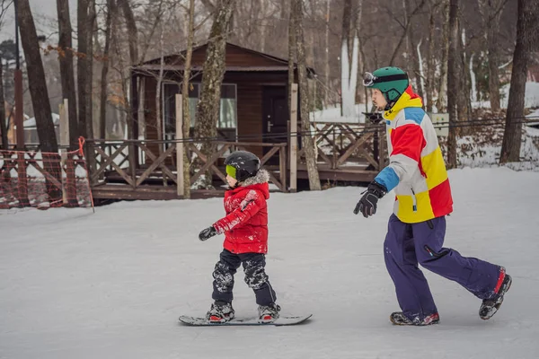 Snowboard instructeur leert een jongen snowboarden. Activiteiten voor kinderen in de winter. Kinderwintersport. Levensstijl — Stockfoto