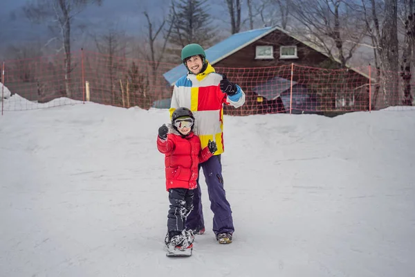 A snowboard oktató megtanít egy fiút snowboardozni. Tevékenységek gyerekeknek télen. Gyermek téli sport. Életmód — Stock Fotó