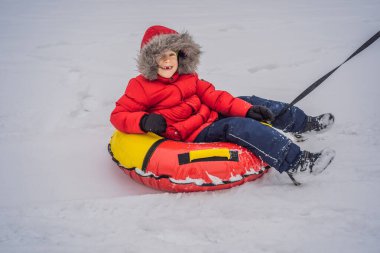 Çocuk kar tüpünde eğleniyor. Çocuk bir boruya biniyor. Çocuklar için kış eğlencesi