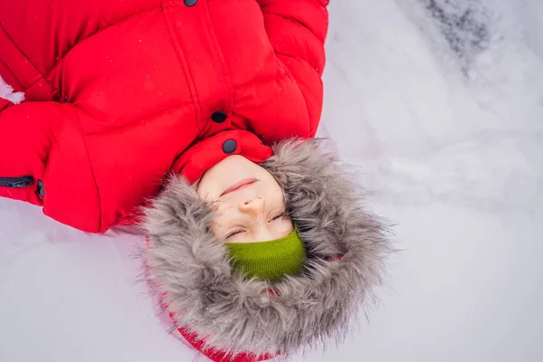 Rapaz feliz brinca com neve. Miúdo giro a atirar neve para um parque de Inverno. Boas férias de inverno. Moda de inverno — Fotografia de Stock